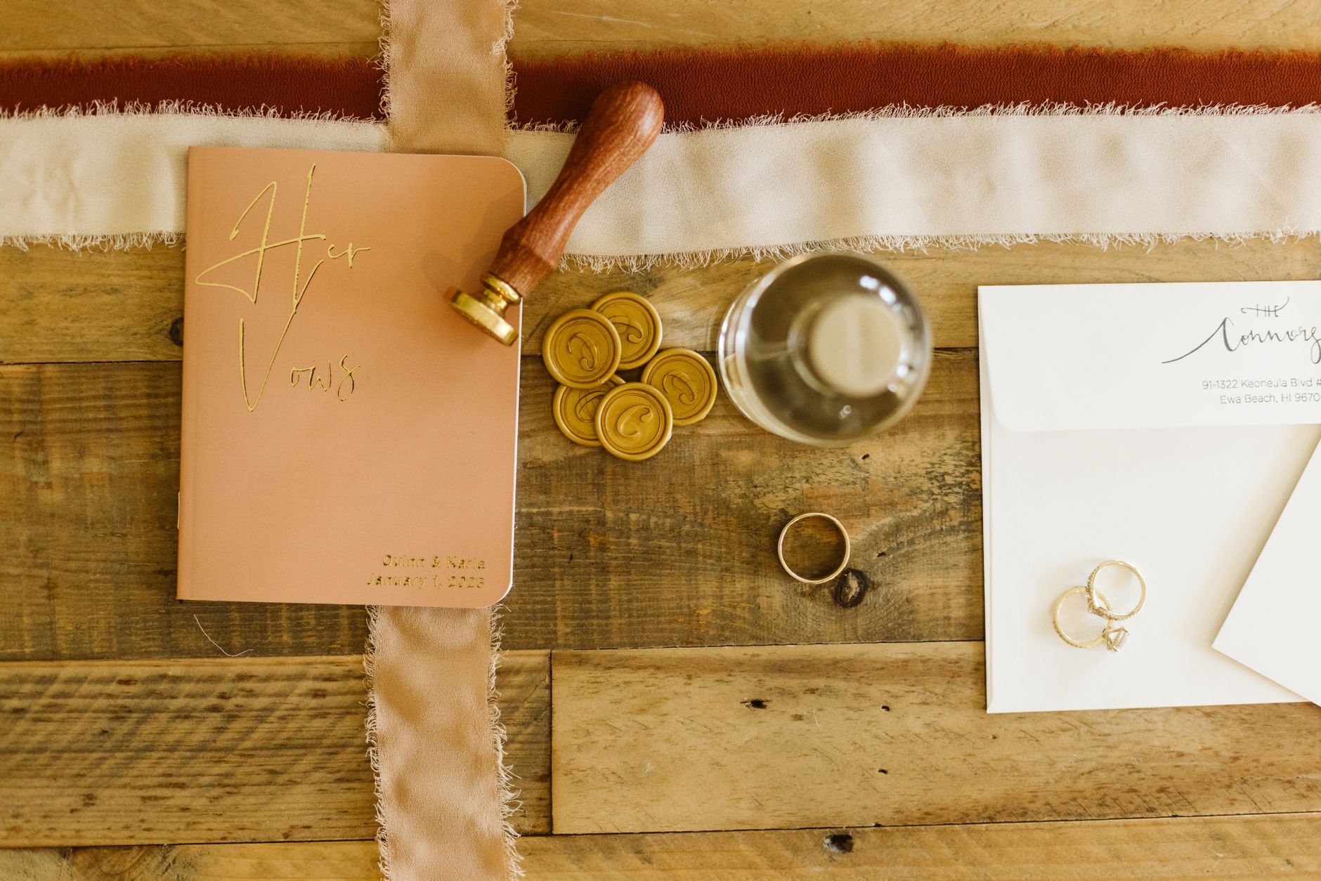 Stylish overhead view of vow book and wedding accessories on rustic table.