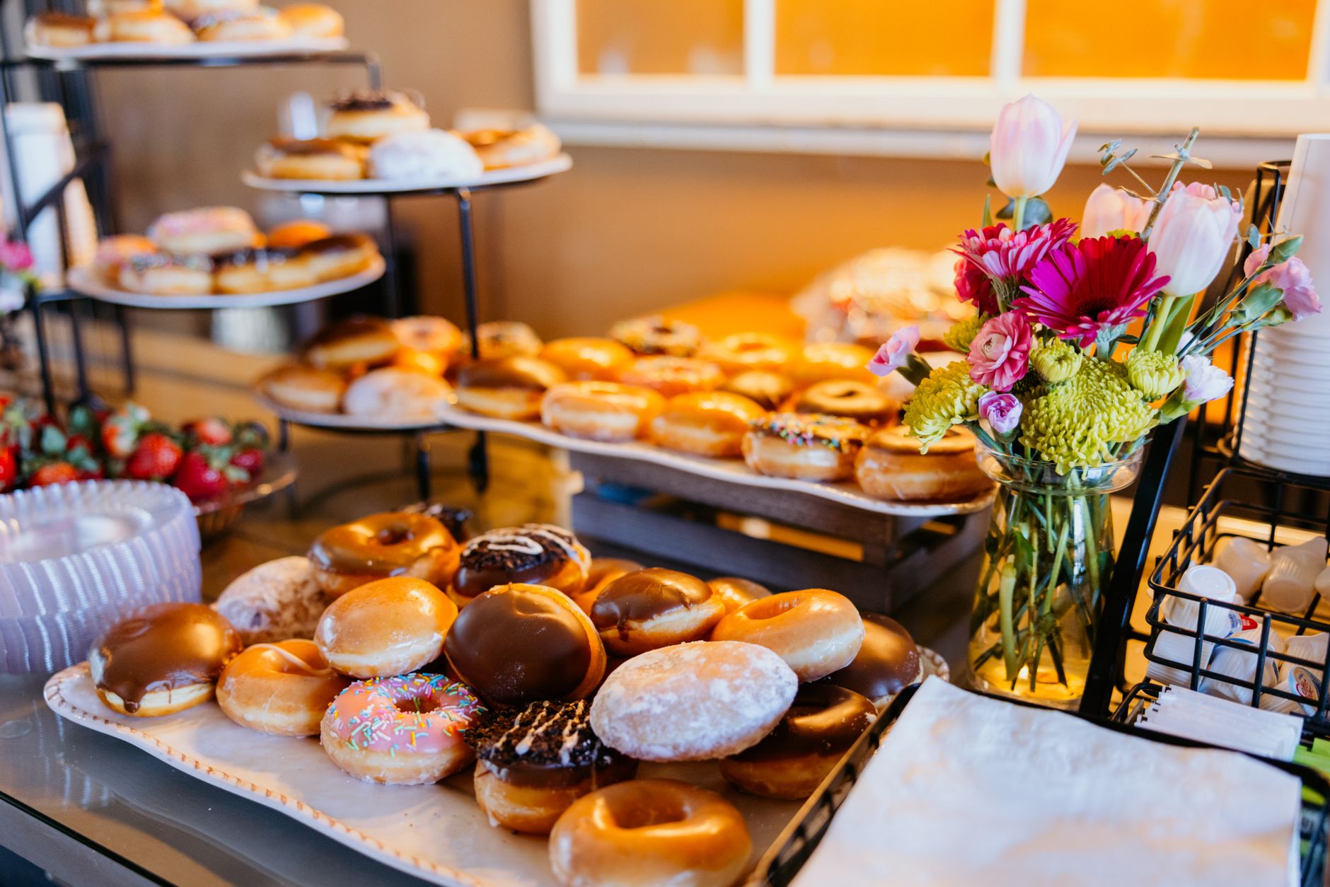 Vibrant assortment of donuts and fresh flowers on display, perfect for sweet tooths and bakery enthusiasts.