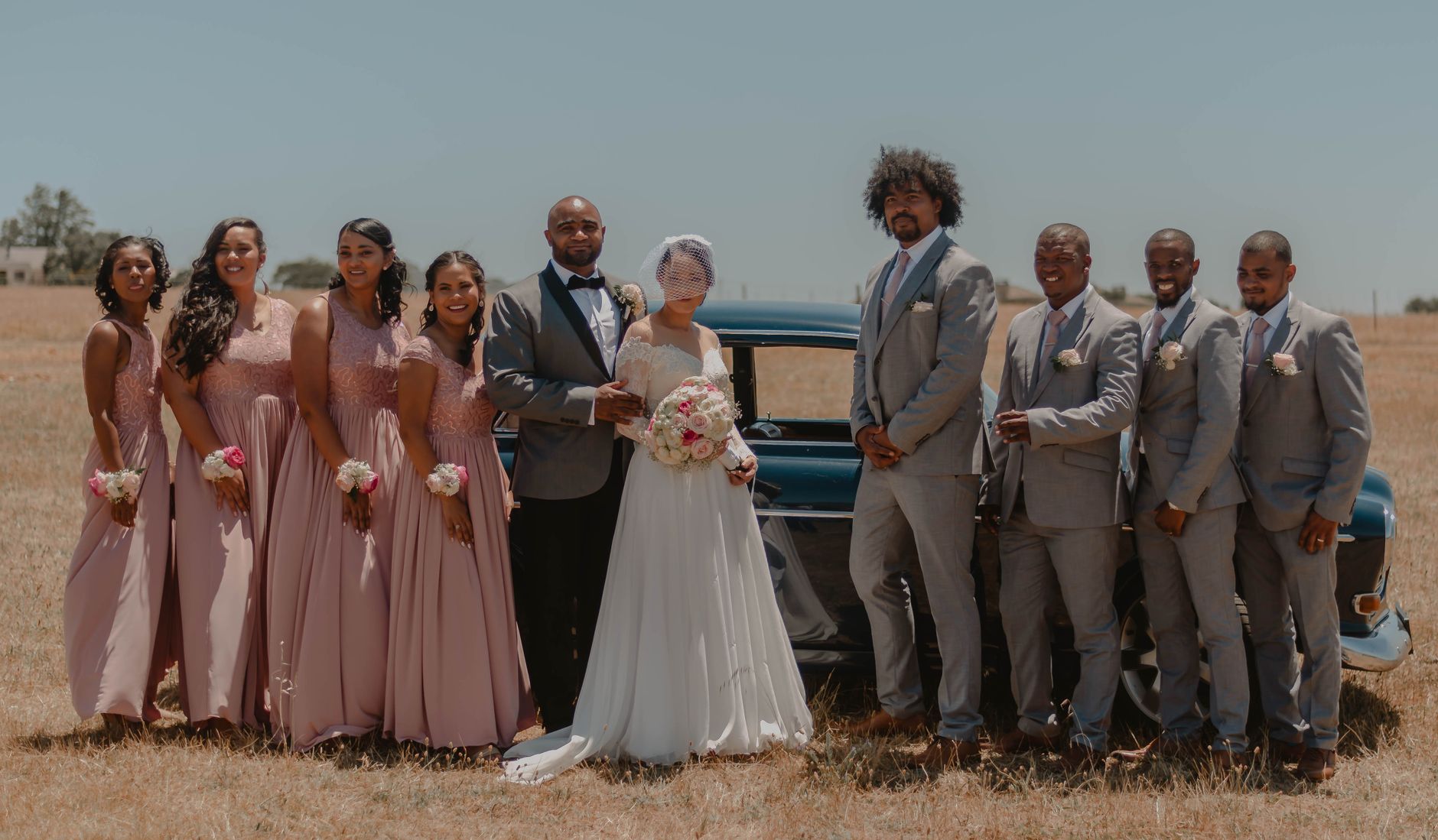 Bride and groom with bridesmaids and groomsmen at outdoor wedding ceremony.