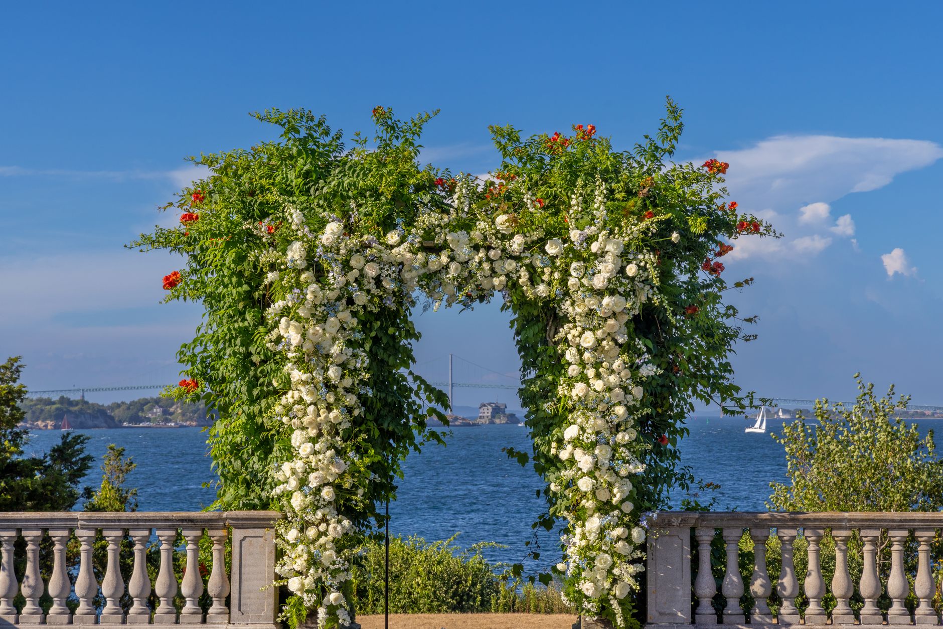 A simple outdoor floral arch framed by a sea view.