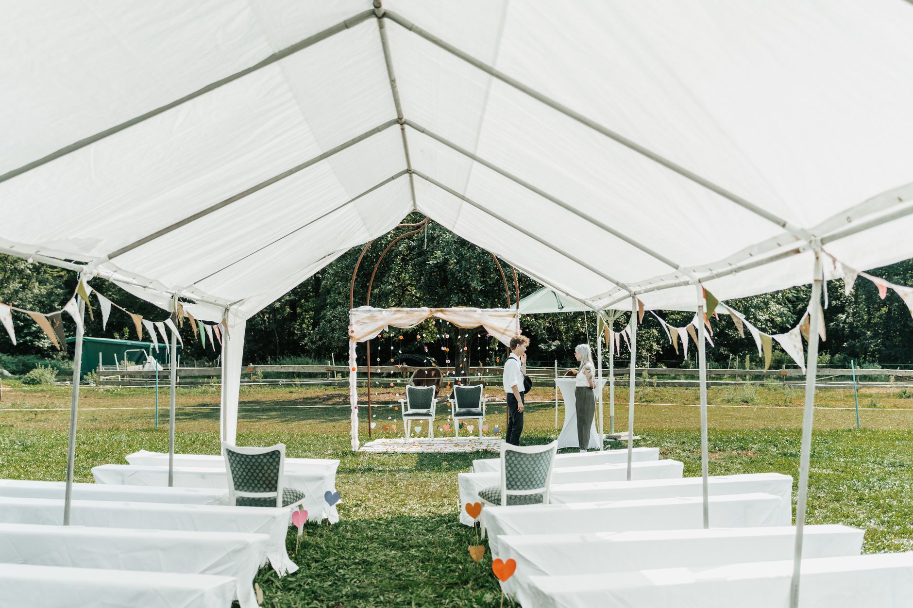 An outdoor wedding ceremony space sheltered beneath a white tent.